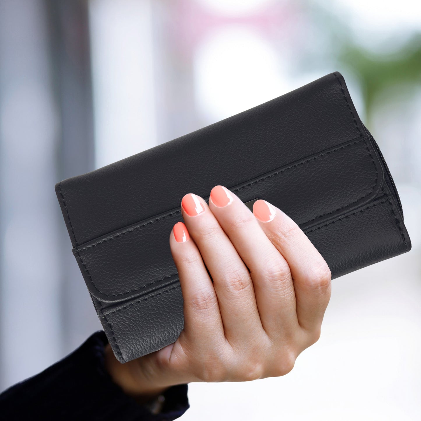 A black RFID leather trifold wallet held in hand, showcasing its compact size and sleek design