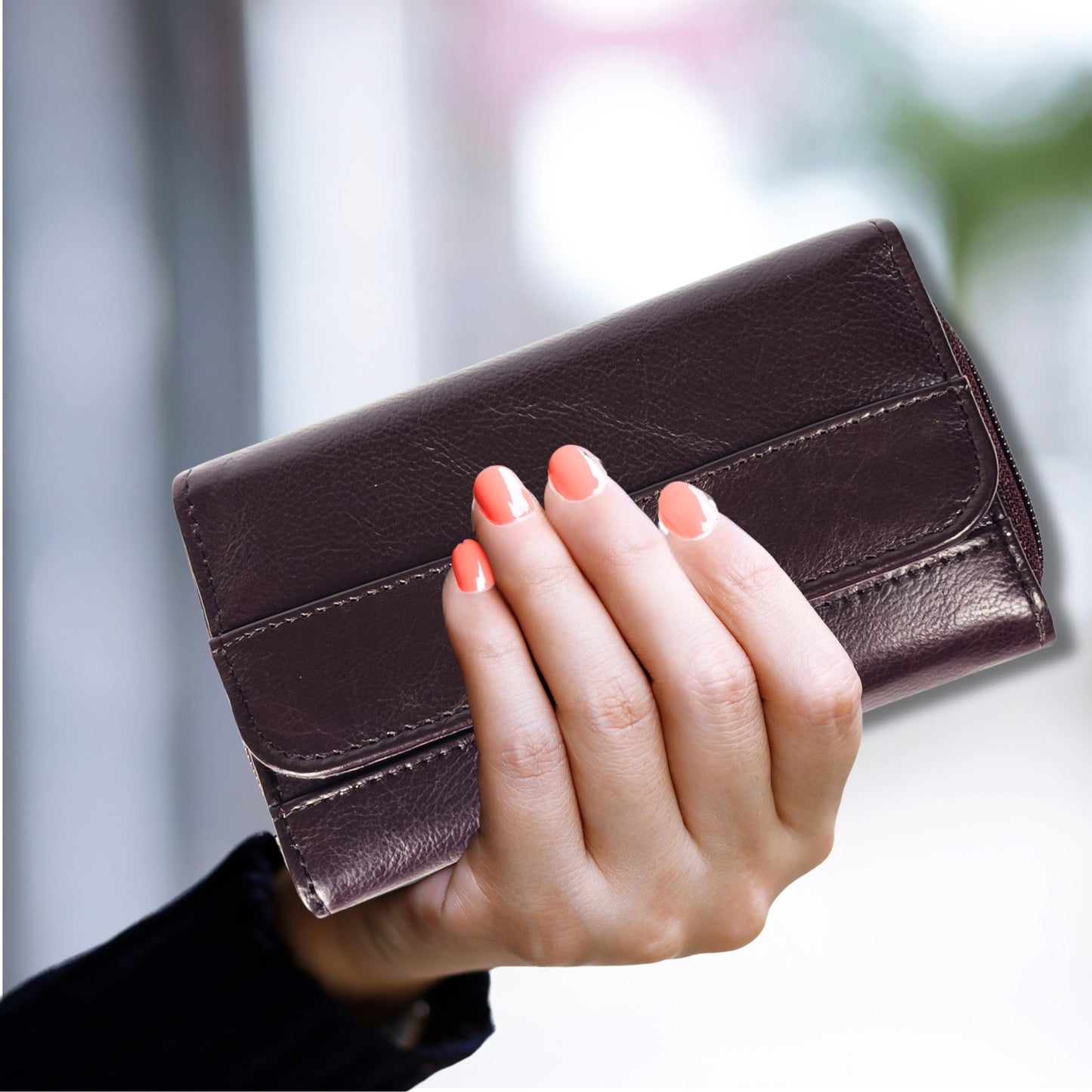 Handheld burgundy RFID soft leather trifold wallet showing scale, seven card slots, ID window, and secure zip coin pocket.