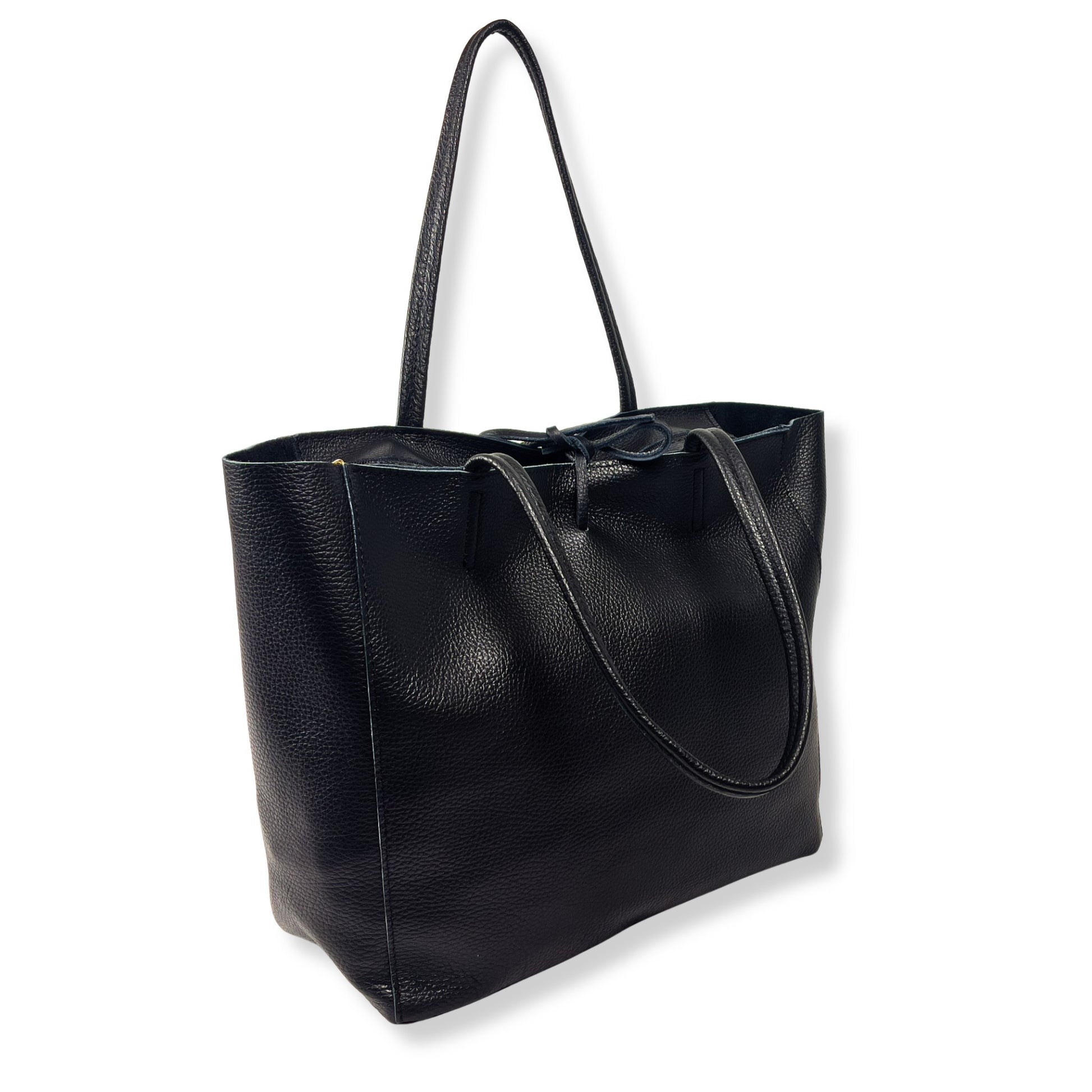Angled front view of black full-grain leather tote bag showing shape and texture under soft light