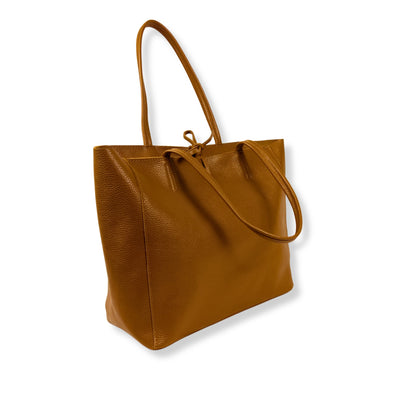 Angled view highlighting texture and tone of dark-tan leather tote bag.