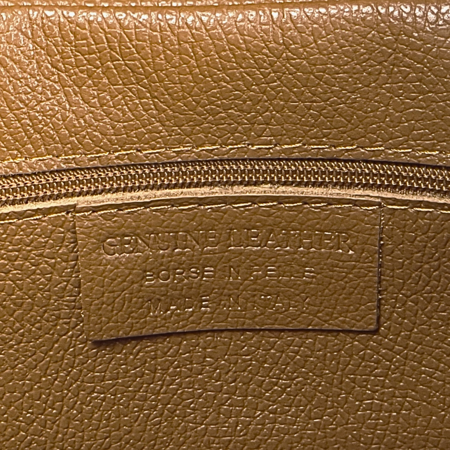Interior stitching close-up showing functional features of the dark-tan real leather tote.