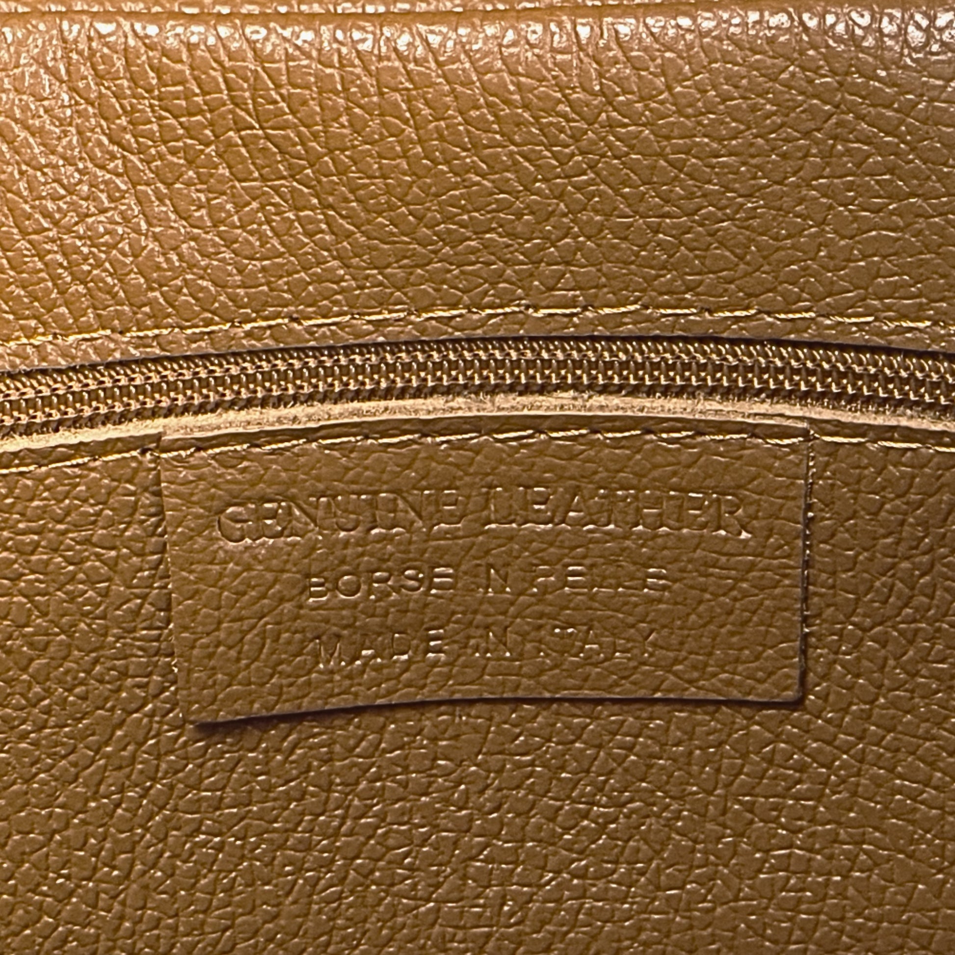 Interior stitching close-up showing functional features of the dark-tan real leather tote.