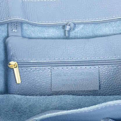 Close up interior detail of denim blue real leather tote showing gold tone zip and precise stitching.