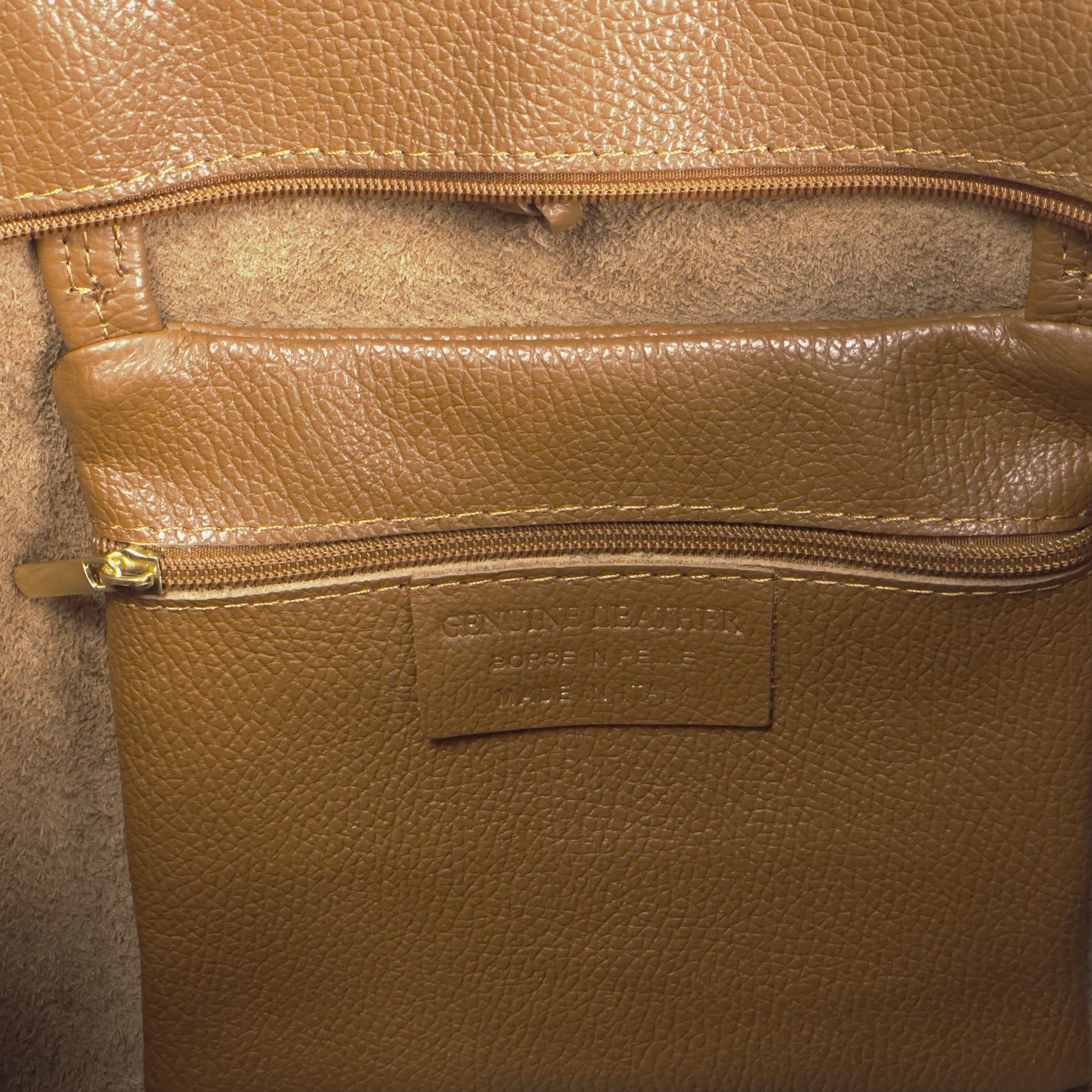 Internal zip pocket close-up showing functional features of the dark-tan real leather tote.