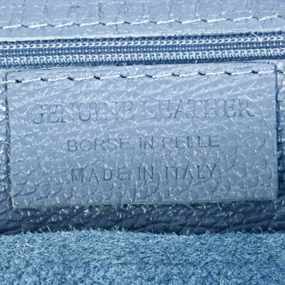 Close up detail of denim blue real leather tote bag showing texture contrast and gold tone zip.