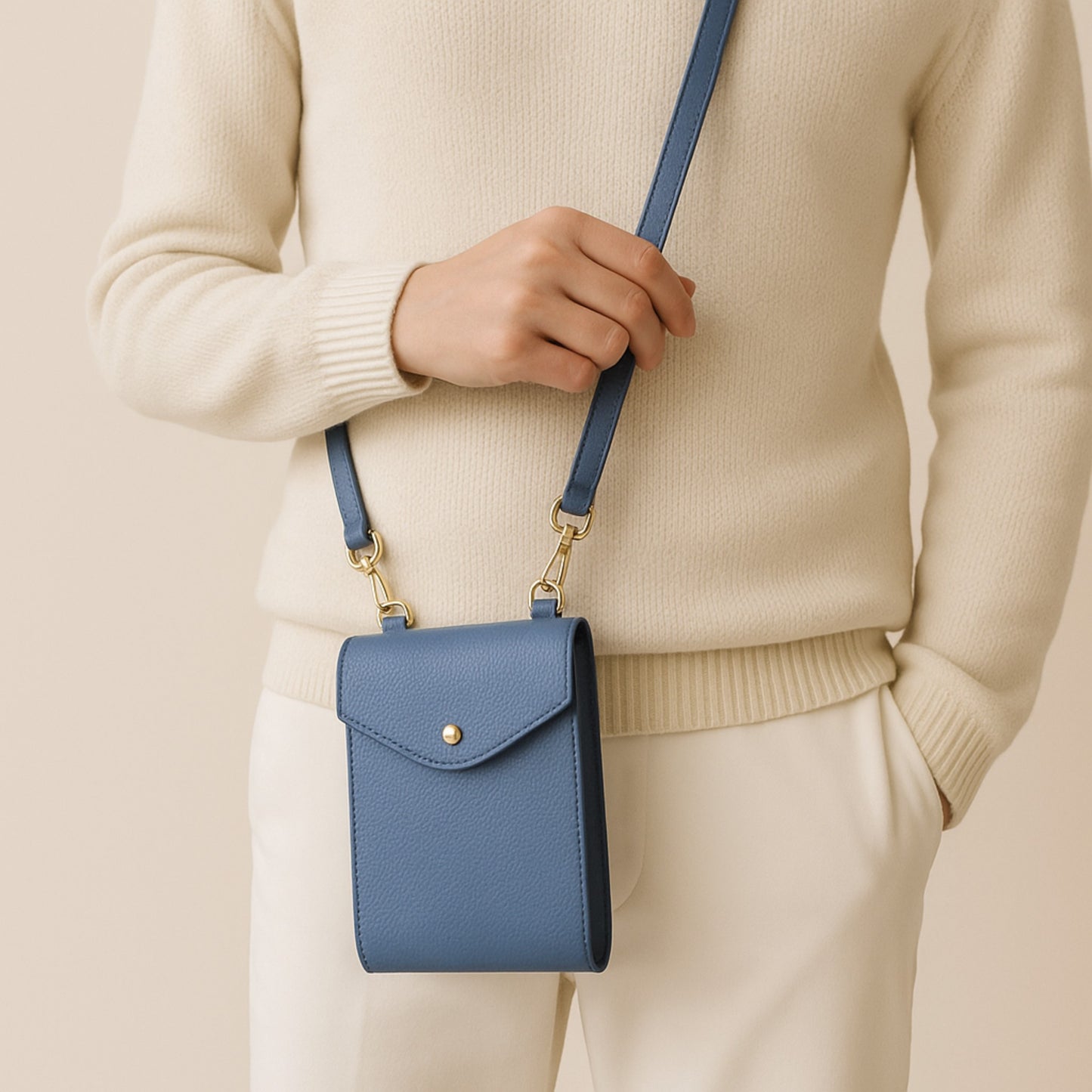 Front view of denim blue real leather crossbody bag with gold hardware and adjustable strap.