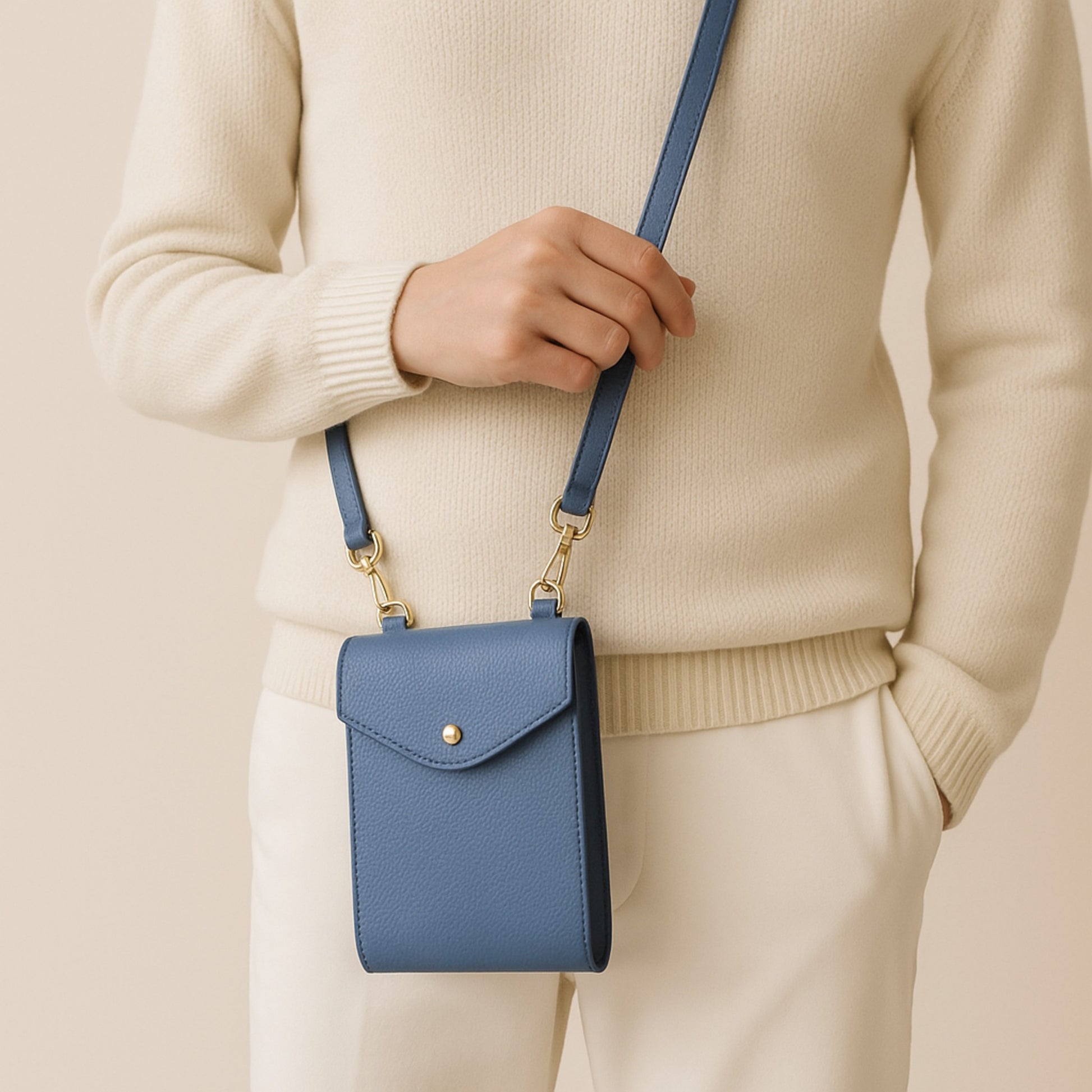 Front view of denim blue real leather crossbody bag with gold hardware and adjustable strap.