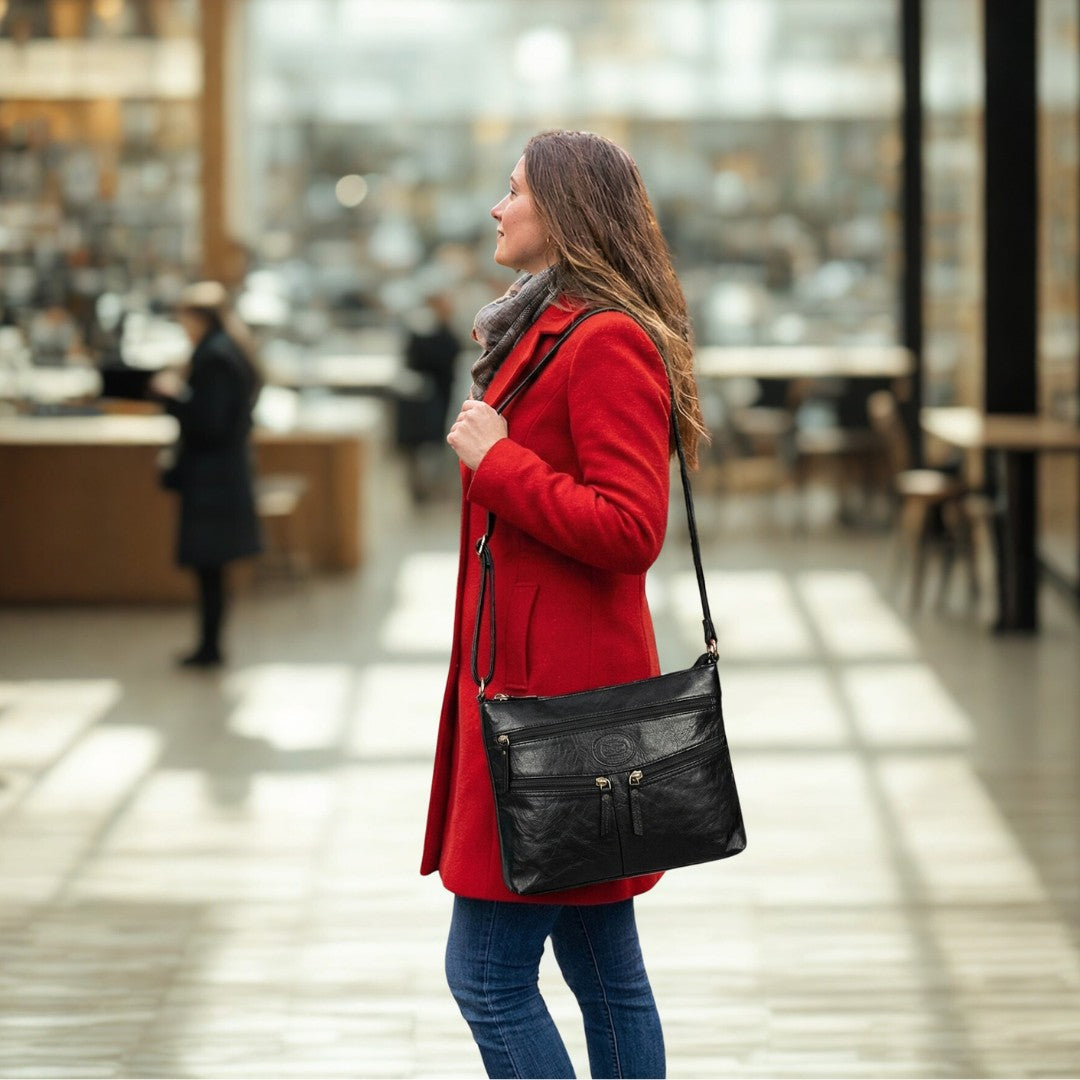 Woman wearing a black leather crossbody bag indoors, showing practical everyday carry in a shopping environment