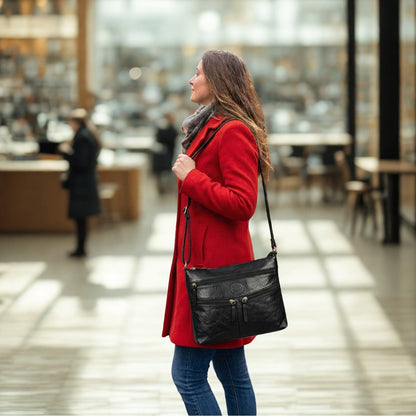 Woman wearing a black leather crossbody bag indoors, showing practical everyday carry in a shopping environment