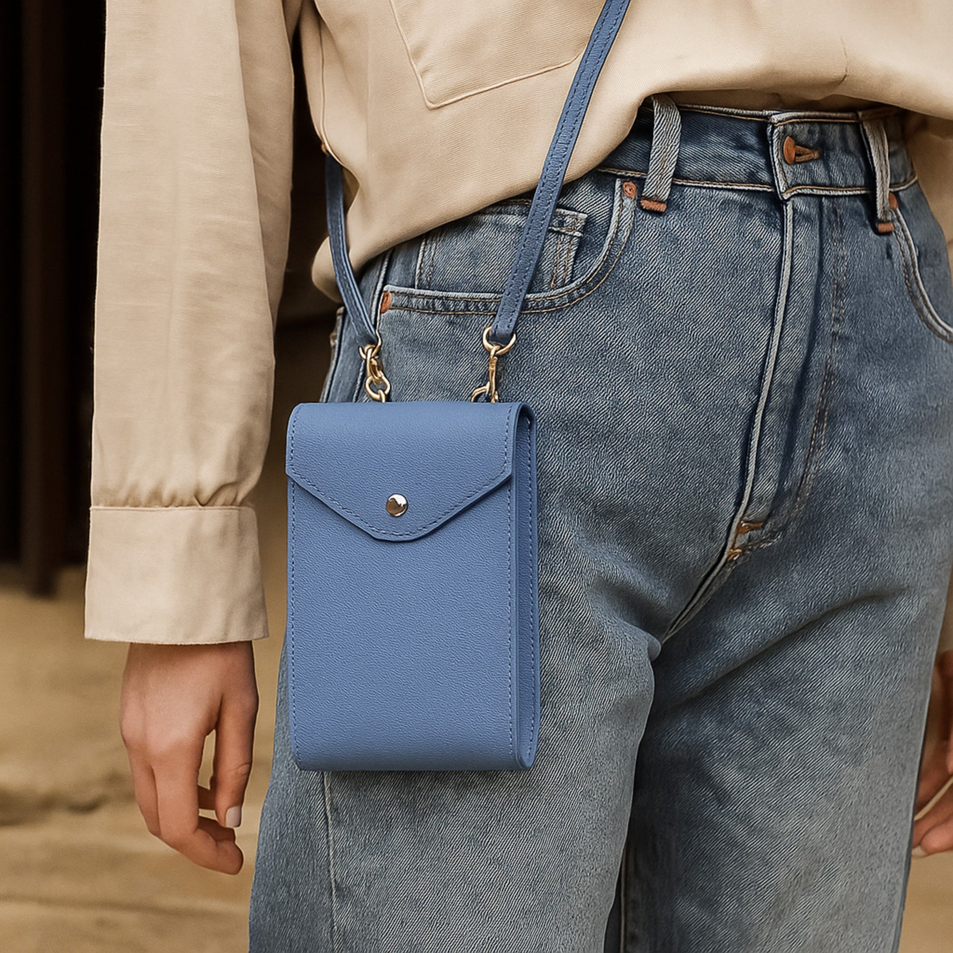 Close-up of denim blue real leather crossbody bag worn against jeans.