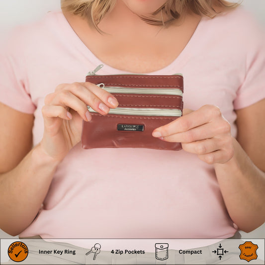 Hand holding a red leather coin purse with multi-zips, showing its small size and practicality