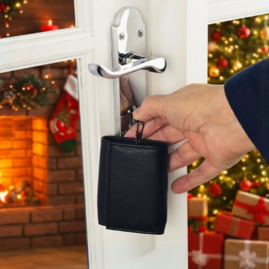Man holding a compact black leather key case at a door with warm festive background lighting